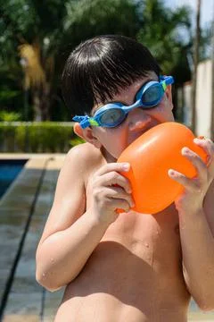 8 year old child with diving goggles biting a water bomb on a sunny day in th Stock Photos