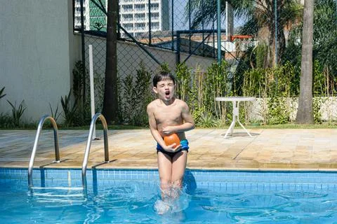 8 year old child making a funny face and diving into the pool with a water bo Stock Photos