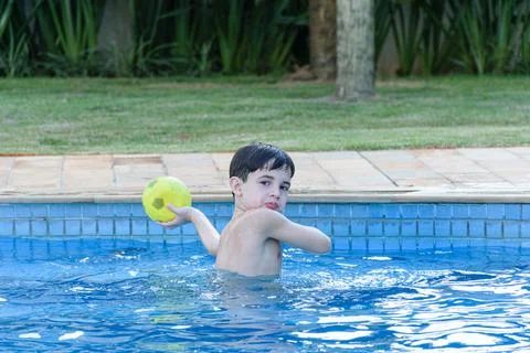 8 year old child in the pool playing throwing the ball. Stock Photos