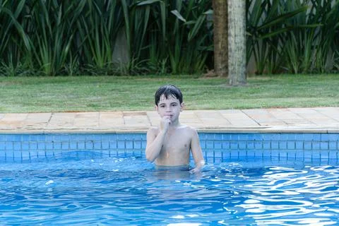 8 year old child in the pool with an apprehensive look and biting his nail. Stock Photos