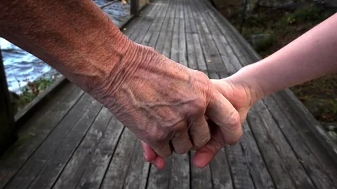 An 8 year old kid and a grandmother holding hands and walking in slow motion Stock Footage 81066526