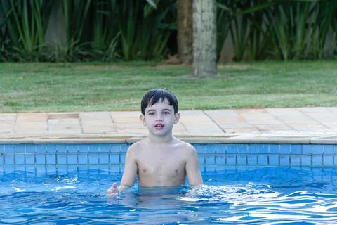 8 year old kid in the pool, waiting for the ball to be thrown for him to catc Stock Photos