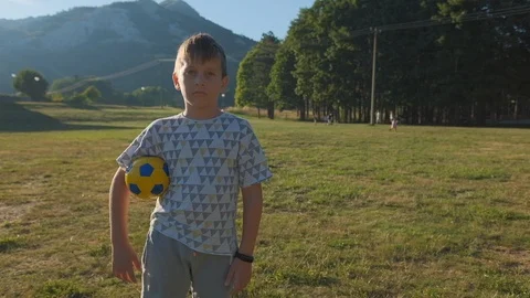 8 years old boy plays soccer on the field at sunset Stock Footage 117281385