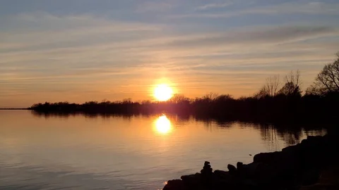 8K 24fps 4320p - The sun sets on the water in 8K after a day in the countryside Stock Footage 129786971