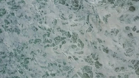 8K Aerial view of natural patterns in sea foam and a wave (29.97 to 23.976 fps) Stock Footage 294119673
