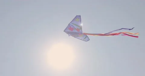 [8K] A Kite flying against a clear blue sky in front of the sun. Stock Footage 210950152