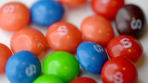 8k macro video colorful candy spinning on white tabletop background Video stock 233203447