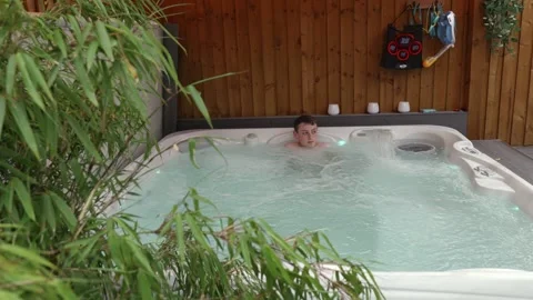 8k, Young boy enjoying a soak in a Hot Tub Spa Jacuzzi. Summer relaxation w.. Stock Footage 241938437