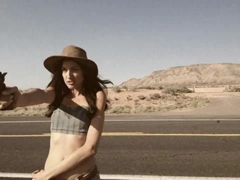 8mm Vintage Style Woman and Gun Crossing Arizona Desert Road Stock Video Stock Footage