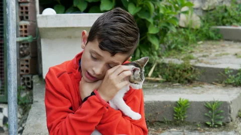 9 year old boy cuddling a kitten, outside Stock Footage 211060627
