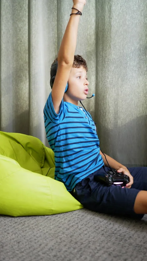 9 year old boy playing video games at home, wearing headphones, vertical image Stock Footage 211044817