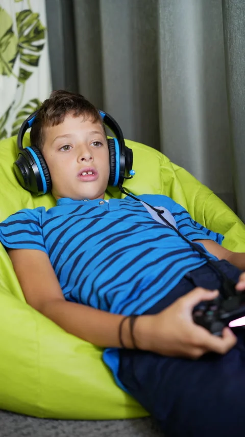 9 year old boy playing video games at home, wearing headphones, vertical image Stock Footage 211045017