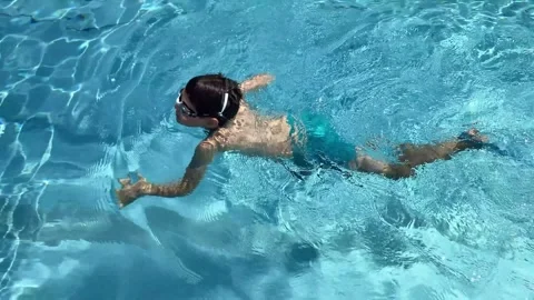 9 year old boy in training fins swimming in outdoor pool in summer. Stock Footage 342030552