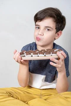 9 year old child holding a tray with several Brazilian fudge balls and pucker Stock Photos