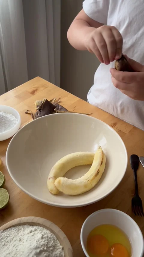 9 years old boy and 1 years baby preparing  a banana cake. Stock Footage 274656596