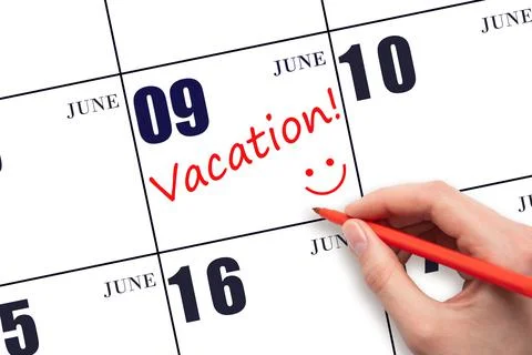 9th day of June. A hand writing a VACATION text and drawing a smiling face on Stock Photos