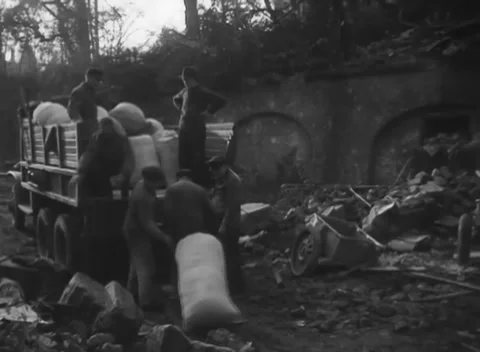 AACHEN, GERMANY - 1944: Sacks lifted from a truck - come off a rubble-side bed Stock Footage 344599577