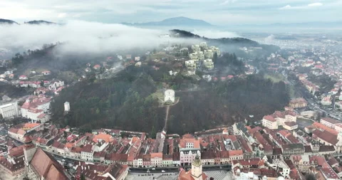Aaerial Panning shot of trees around famous buidings and city, Brasov in Romania Stock Footage 198225265