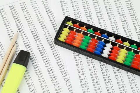Abacus for mental arithmetic, against the background of examples to solve. Stock Photos