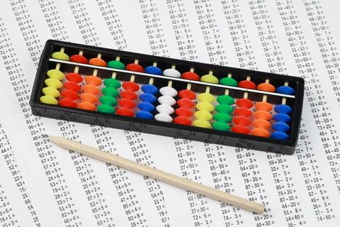 Abacus for mental arithmetic, against the background of examples to solve. Stock Photos