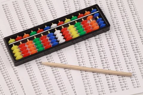 Abacus for mental arithmetic, against the background of examples to solve. Stock Photos