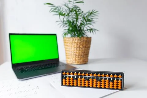 Abacus for mental arithmetic on a table with a laptop chroma key background.. Stock Photos