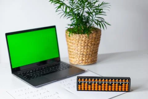 Abacus for mental arithmetic on a table with a laptop chroma key background.. Stock Photos