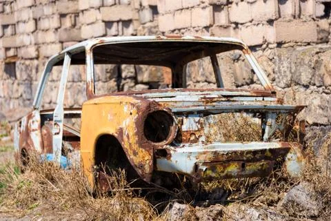 Abandoned and rusty skeleton of a Soviet Russian car growing hay inside by th Stock Photos
