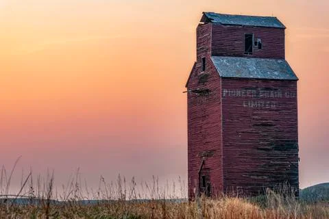 Abandoned and weathered grain elevator at sunset on the Canadian Prairies; Va 스톡 사진