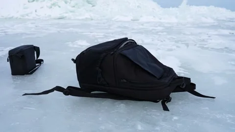 Abandoned backpack and small bag on frozen ocean ice near a pressure ridge Stock Footage 332066999