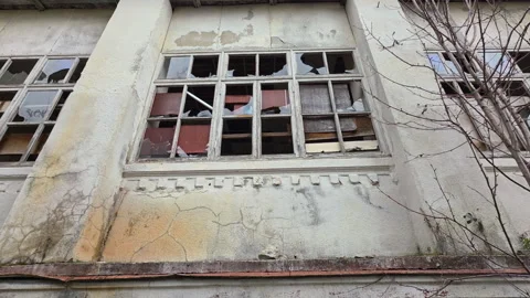 Abandoned building with broken windows reflecting the sky, decaying facade of a Vídeo Stock 329747864