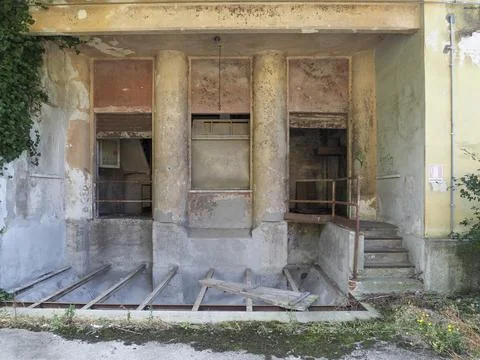 Abandoned building facade with broken windows and overgrown vegetation Stock Photos
