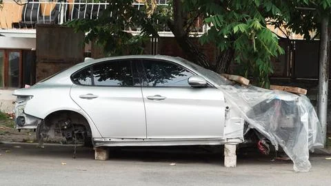 Abandoned car frame on blocks under tree. Stock Photos