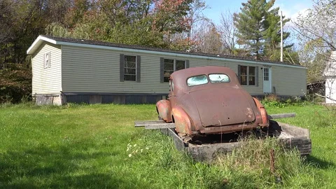 An abandoned car sits on blocks outside a trailer home in rural America. Stock Footage 83310970