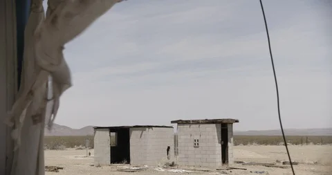 Abandoned Cement Shacks with Tattered Curtains in the Foreground Stock Footage 89943220