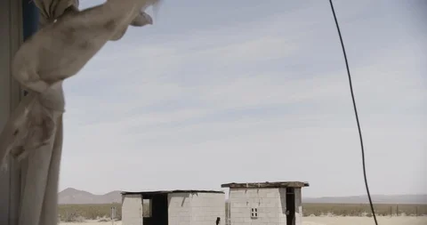 Abandoned Cement Shacks with Tattered Curtains in the Foreground - Tilt Down Stock Footage 89943221