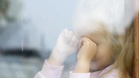 Abandoned child crying at the window Stock Photos
