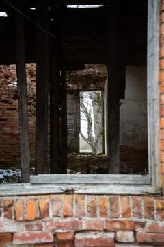 Abandoned collapsed red brick building interior through an old wooden window Stock Photos