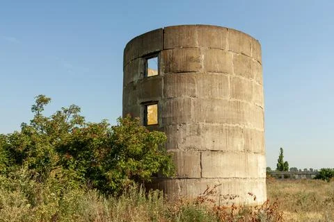 Abandoned concrete silo structure with broken windows in a rural landscape Stock Photos