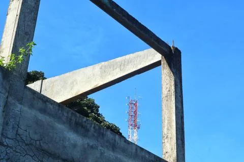 Abandoned concrete structure frames a modern telecommunications tower Stock Photos