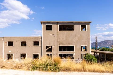 Abandoned derelict building with broken windows and weathered facade Stock Photos