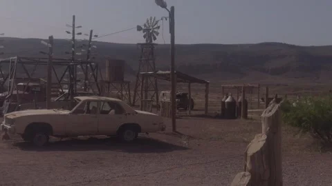 Abandoned desert scrapyard with old car and windmill in Morocco Stock Footage 337780894