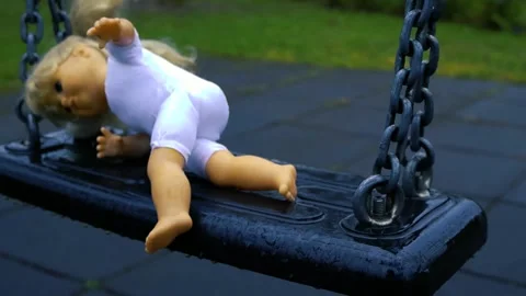 Abandoned Doll Swinging on a Wet Playground in Slow Motion Stock Footage 334647853