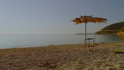 An abandoned empty beach with palm-leaf umbrella and an old table in the golden Stock Footage 122453786