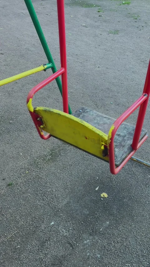 Abandoned empty swing seat slowly swaying on grim background. Neglected and lost Stock-Footage 292559689