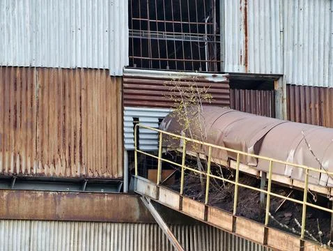 Abandoned factory with weathered elements. Rusted pathway and overgrown fac.. Foto stock