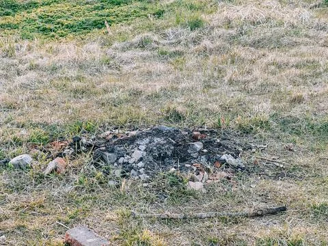 Abandoned Fire Pit with Ashes in Dry Grass Field Фото