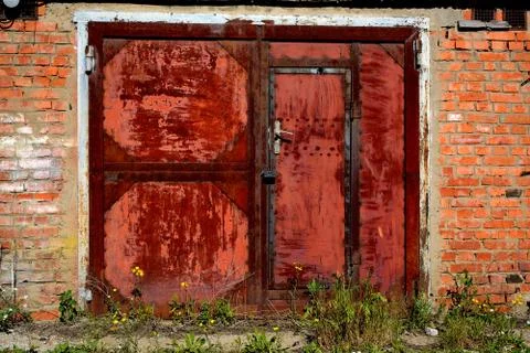 An abandoned garage with a rusty gate.	 Stock Photos