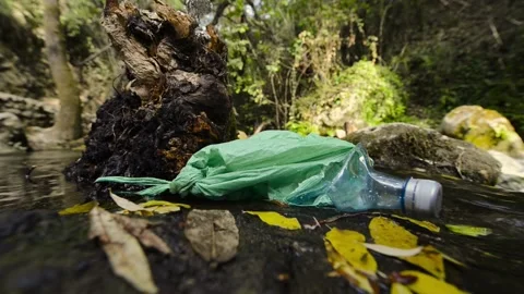 Abandoned garbage on the shore of a stream of clean water. Stock Footage 135605969
