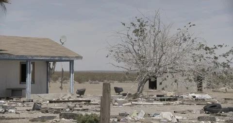 Abandoned House with Junk in Front Yard in Desert - Tree in Foreground Stock Footage 89943107